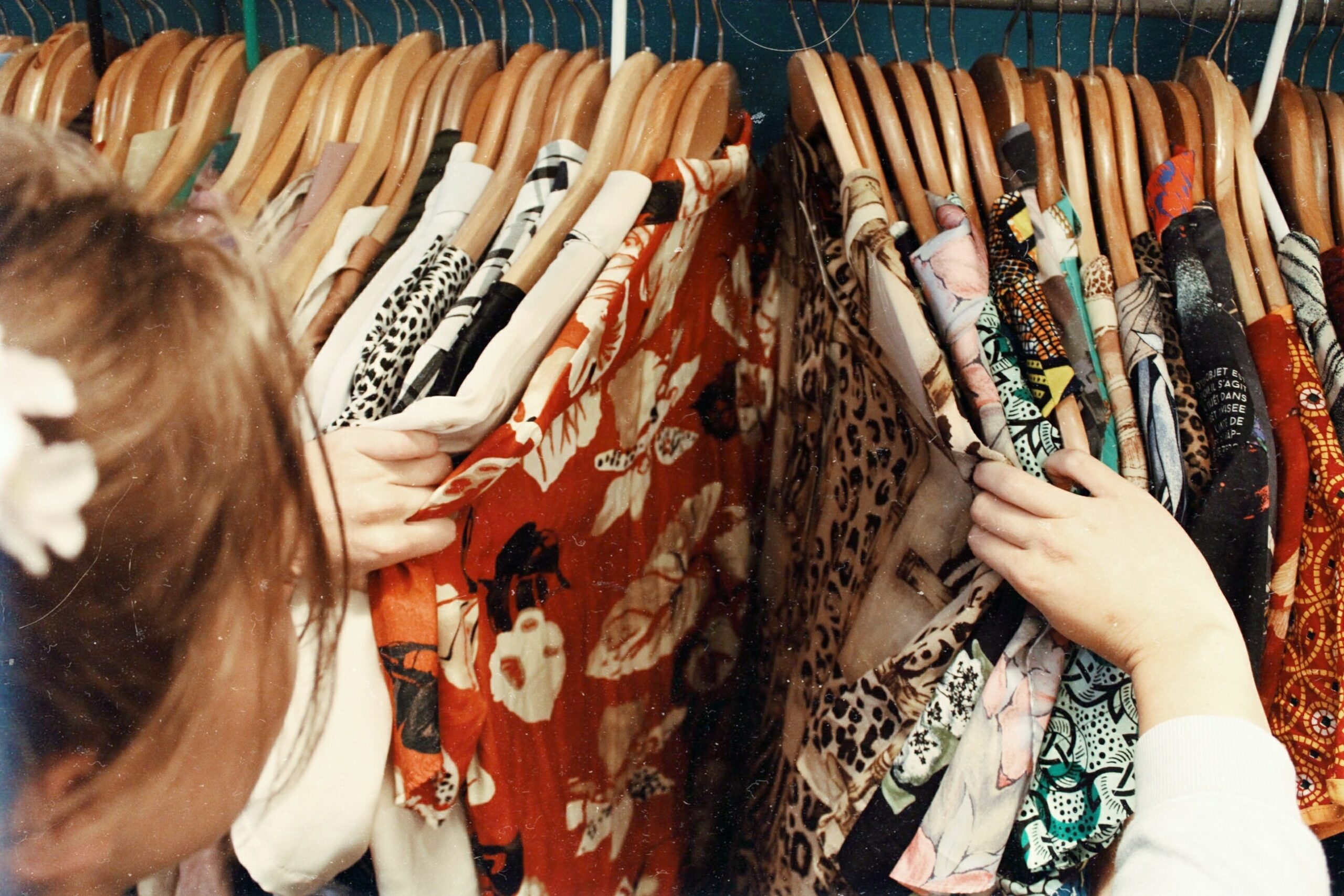 Premier plan d'une cliente vue de dos choisissant parmi les chemises exposées au showroom de Simpl Vintage